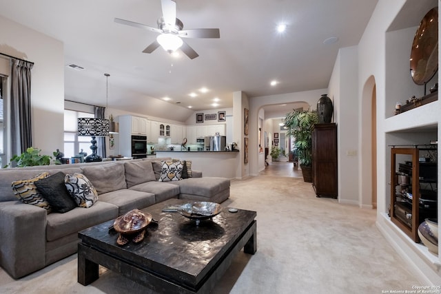 living room with visible vents, arched walkways, light colored carpet, lofted ceiling, and ceiling fan