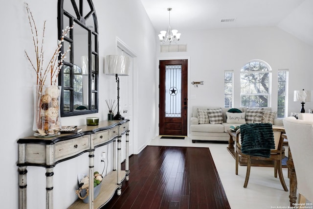 foyer entrance with vaulted ceiling, wood finished floors, visible vents, and an inviting chandelier