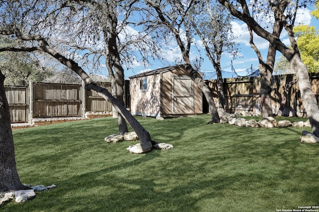 view of yard with a storage shed, a fenced backyard, and an outbuilding