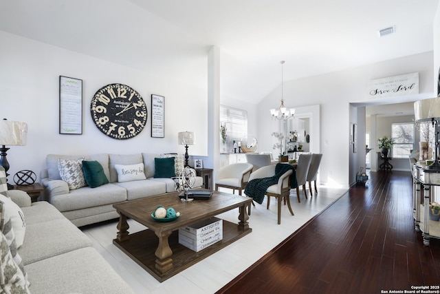 living room featuring lofted ceiling, wood finished floors, visible vents, and a chandelier