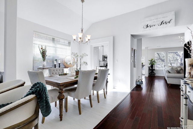 dining room featuring dark wood-style floors, a chandelier, vaulted ceiling, and baseboards