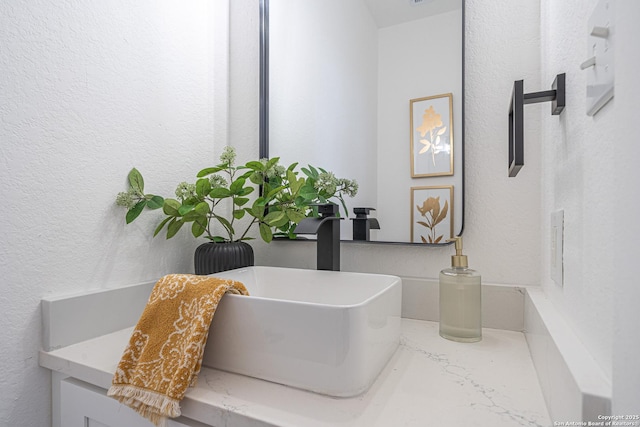 bathroom featuring a textured wall and vanity
