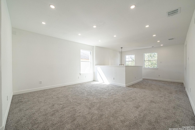 empty room featuring carpet floors, baseboards, visible vents, and recessed lighting