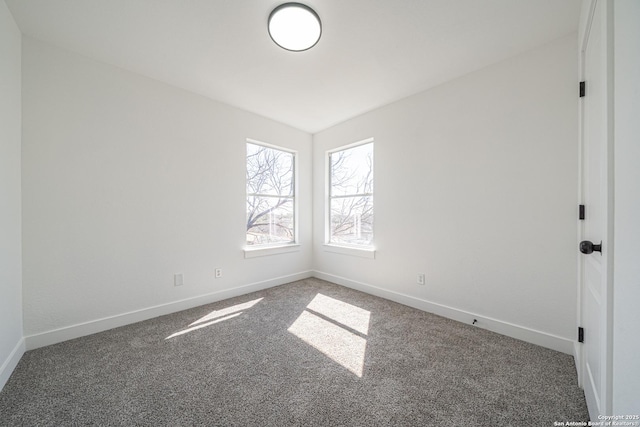 unfurnished room featuring dark colored carpet and baseboards