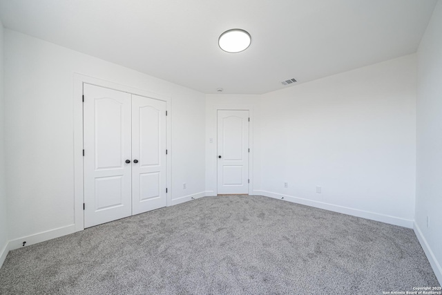 unfurnished bedroom with carpet floors, baseboards, visible vents, and a closet