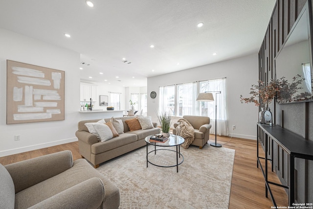 living room with light wood-style floors, recessed lighting, visible vents, and baseboards