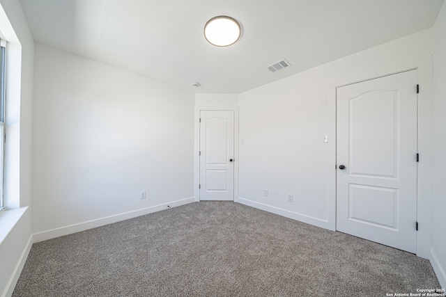 spare room with carpet, visible vents, and baseboards