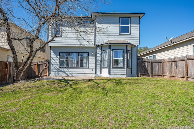 rear view of property with a fenced backyard and a lawn