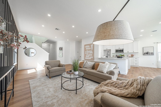 living room with light wood-style floors, baseboards, visible vents, and recessed lighting