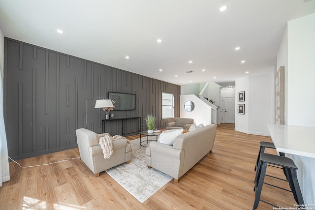 living area featuring light wood-style flooring, stairway, baseboards, and recessed lighting