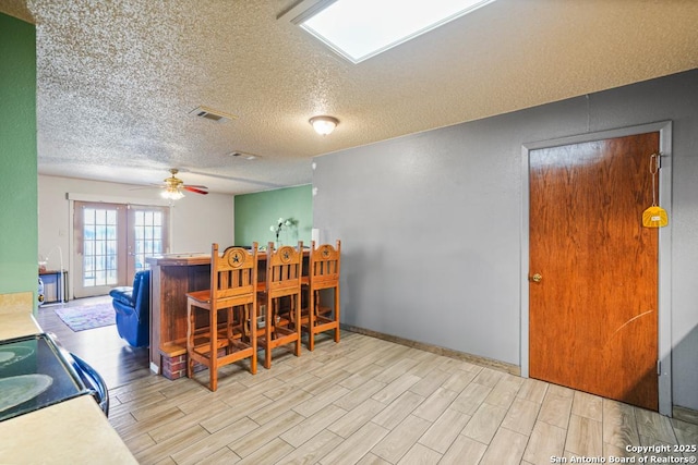 dining room featuring ceiling fan, a dry bar, wood finish floors, and visible vents