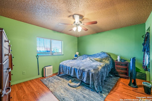 bedroom featuring a textured ceiling, ceiling fan, wood finished floors, and baseboards