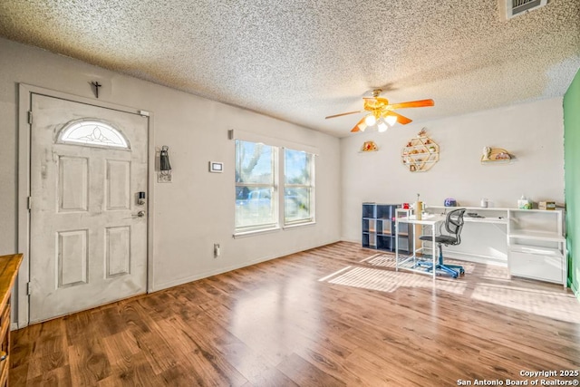 entryway with baseboards, visible vents, ceiling fan, wood finished floors, and a textured ceiling