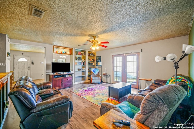 living area featuring french doors, light wood finished floors, visible vents, a ceiling fan, and a textured ceiling