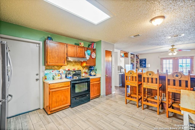 kitchen featuring freestanding refrigerator, light countertops, visible vents, and black / electric stove