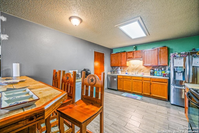 kitchen with a sink, light countertops, brown cabinets, and stainless steel appliances