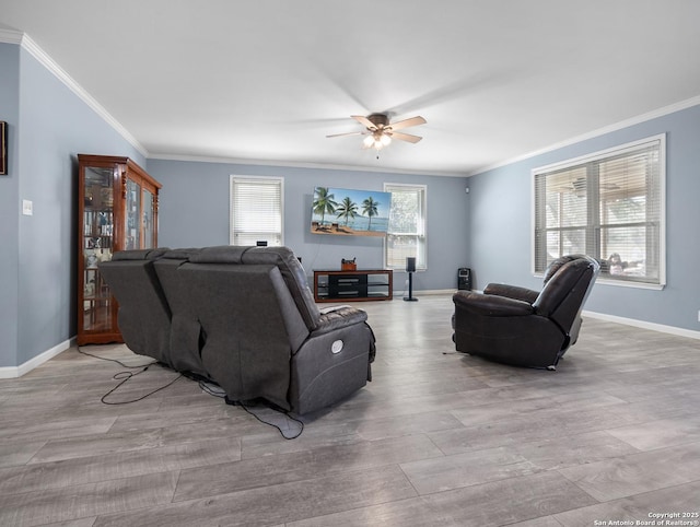 living room featuring crown molding, light wood-style flooring, baseboards, and ceiling fan