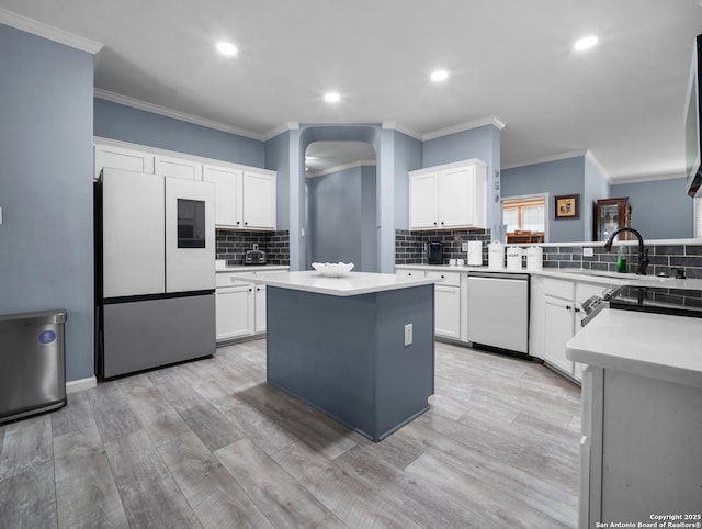 kitchen with light countertops, appliances with stainless steel finishes, a kitchen island, and white cabinets