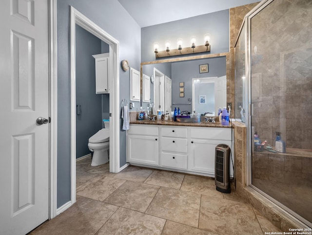 bathroom with double vanity, a stall shower, a sink, and toilet