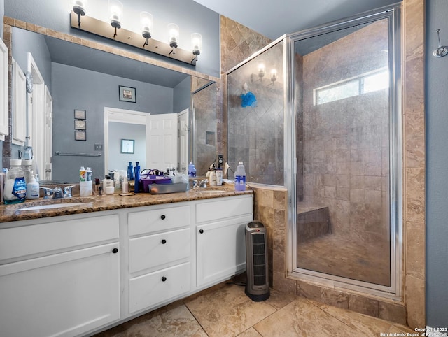 bathroom featuring double vanity, a stall shower, and a sink