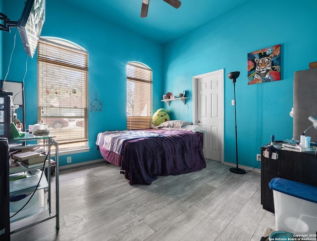 bedroom with ceiling fan, light wood-type flooring, and baseboards