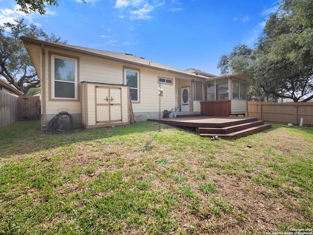 rear view of property featuring a deck, a lawn, a fenced backyard, and a sunroom