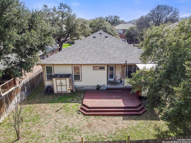 rear view of house featuring a deck, a fenced backyard, an outdoor structure, a lawn, and a storage unit