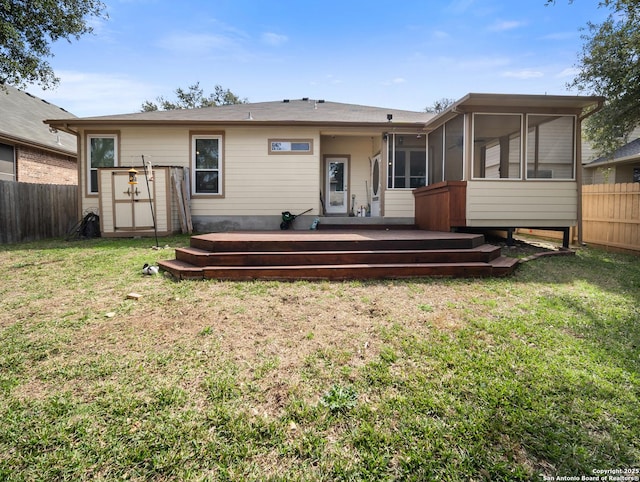 back of house featuring a sunroom, fence, a deck, and a lawn