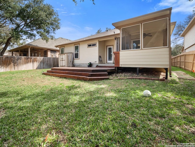 back of house featuring a lawn, a fenced backyard, a wooden deck, and a sunroom