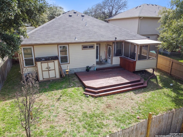 rear view of property featuring a wooden deck, a yard, a fenced backyard, and a sunroom