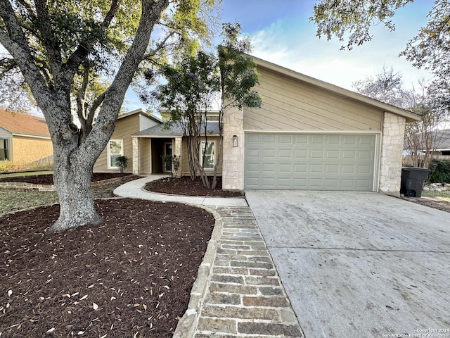 mid-century modern home featuring driveway, stone siding, and an attached garage