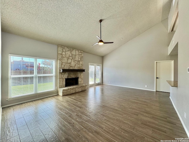 unfurnished living room featuring ceiling fan, a textured ceiling, a fireplace, wood finished floors, and french doors