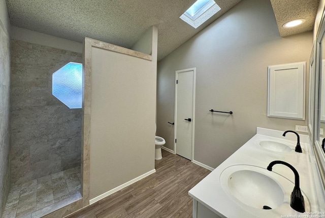 bathroom with lofted ceiling with skylight, walk in shower, a sink, and double vanity