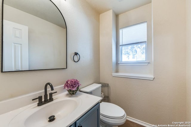 bathroom with toilet, vanity, and baseboards