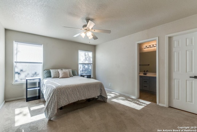 bedroom with light carpet, baseboards, ceiling fan, ensuite bathroom, and a textured ceiling