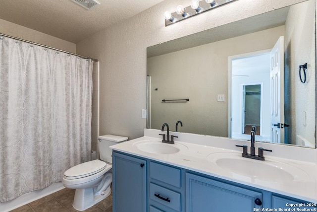 bathroom with tile patterned flooring, a sink, toilet, and double vanity