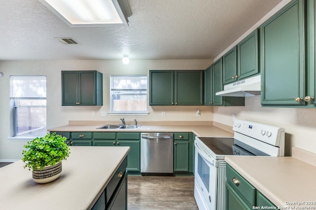 kitchen with white range with electric cooktop, green cabinets, stainless steel dishwasher, a sink, and under cabinet range hood