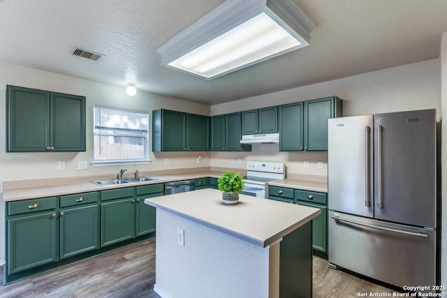 kitchen featuring stainless steel appliances, light countertops, a sink, a kitchen island, and under cabinet range hood