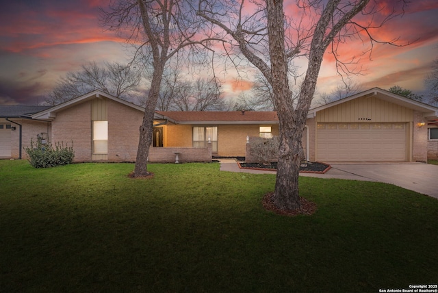 view of front of property with an attached garage, brick siding, concrete driveway, and a yard