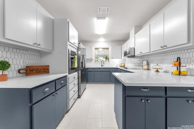 kitchen with visible vents, decorative backsplash, stainless steel appliances, blue cabinetry, and white cabinetry