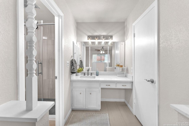 full bathroom featuring a stall shower, tile patterned flooring, a textured wall, and vanity