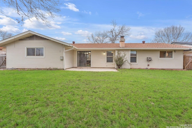 rear view of property featuring a patio area, a chimney, fence, and a lawn