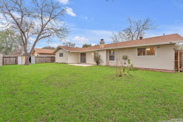 rear view of property featuring a yard, a fenced backyard, a patio, and a chimney