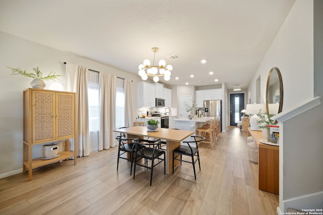 dining area featuring light wood-style flooring, visible vents, a chandelier, and baseboards