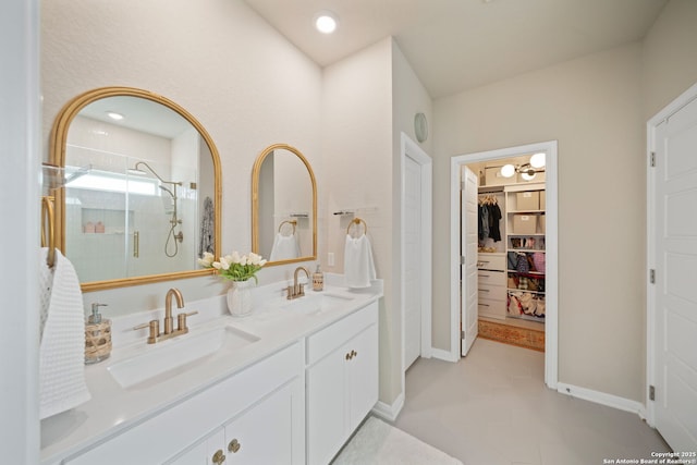 full bathroom featuring a walk in closet, a sink, baseboards, and double vanity