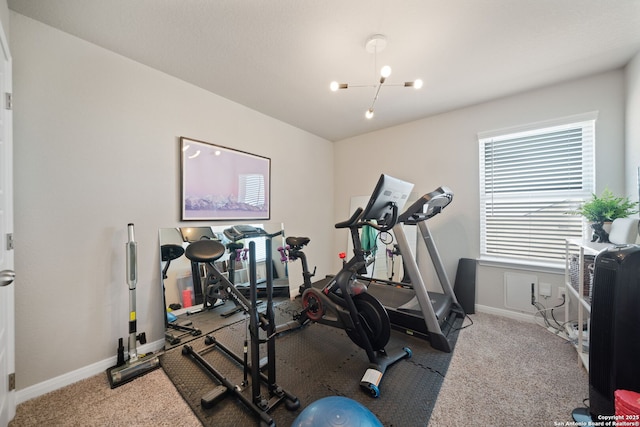 workout room with an inviting chandelier, carpet, and baseboards