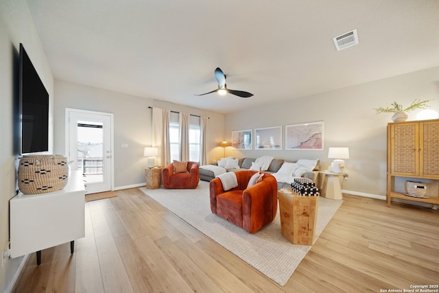 living room featuring light wood-type flooring, visible vents, ceiling fan, and baseboards