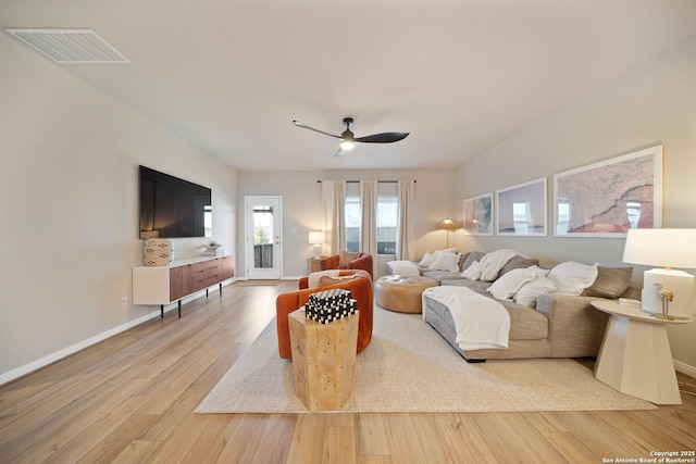 living area with baseboards, visible vents, and wood finished floors