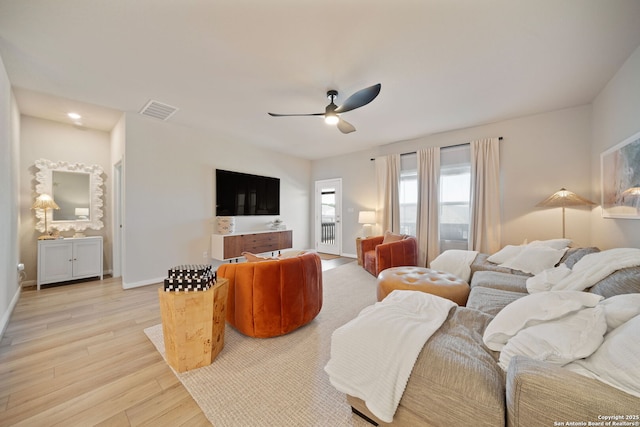 living area featuring light wood-style floors, visible vents, ceiling fan, and baseboards