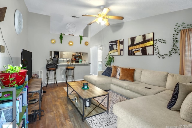 living area with baseboards, visible vents, ceiling fan, dark wood-type flooring, and vaulted ceiling